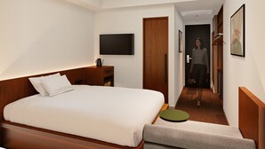 A hotel room with a large bed, a TV mounted on the wall, a wooden wardrobe, and a hallway leading to another room. - Hotel Gracery Tokyo Tamachi (Tokyo)