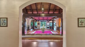 An arched entrance with a central floral arrangement, wooden beams, and framed pictures on the walls. - Club Mahindra Madikeri, Coorg (Madikeri)