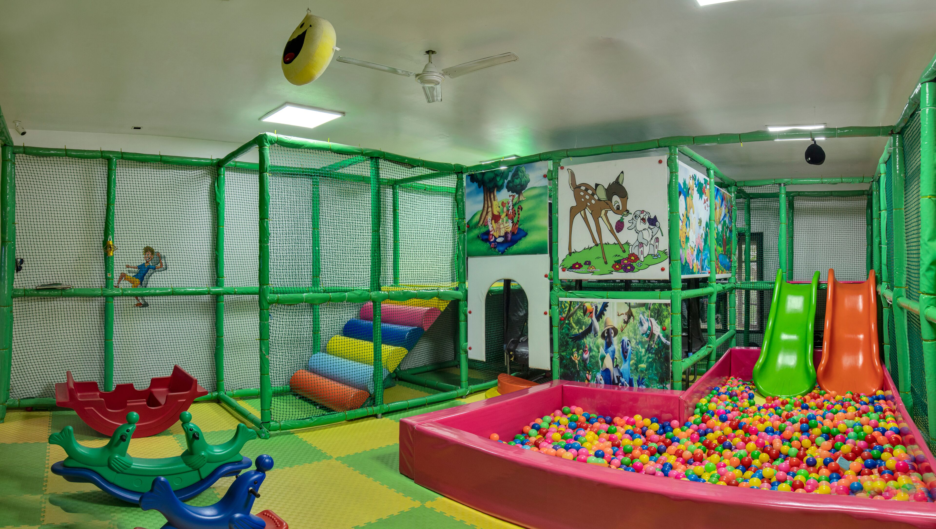 Zona de juegos infantiles con piscina de pelotas, toboganes y una estructura para escalar.