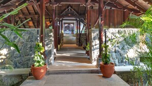 A covered walkway with stone walls and potted plants. - Club Mahindra Madikeri, Coorg (Madikeri)