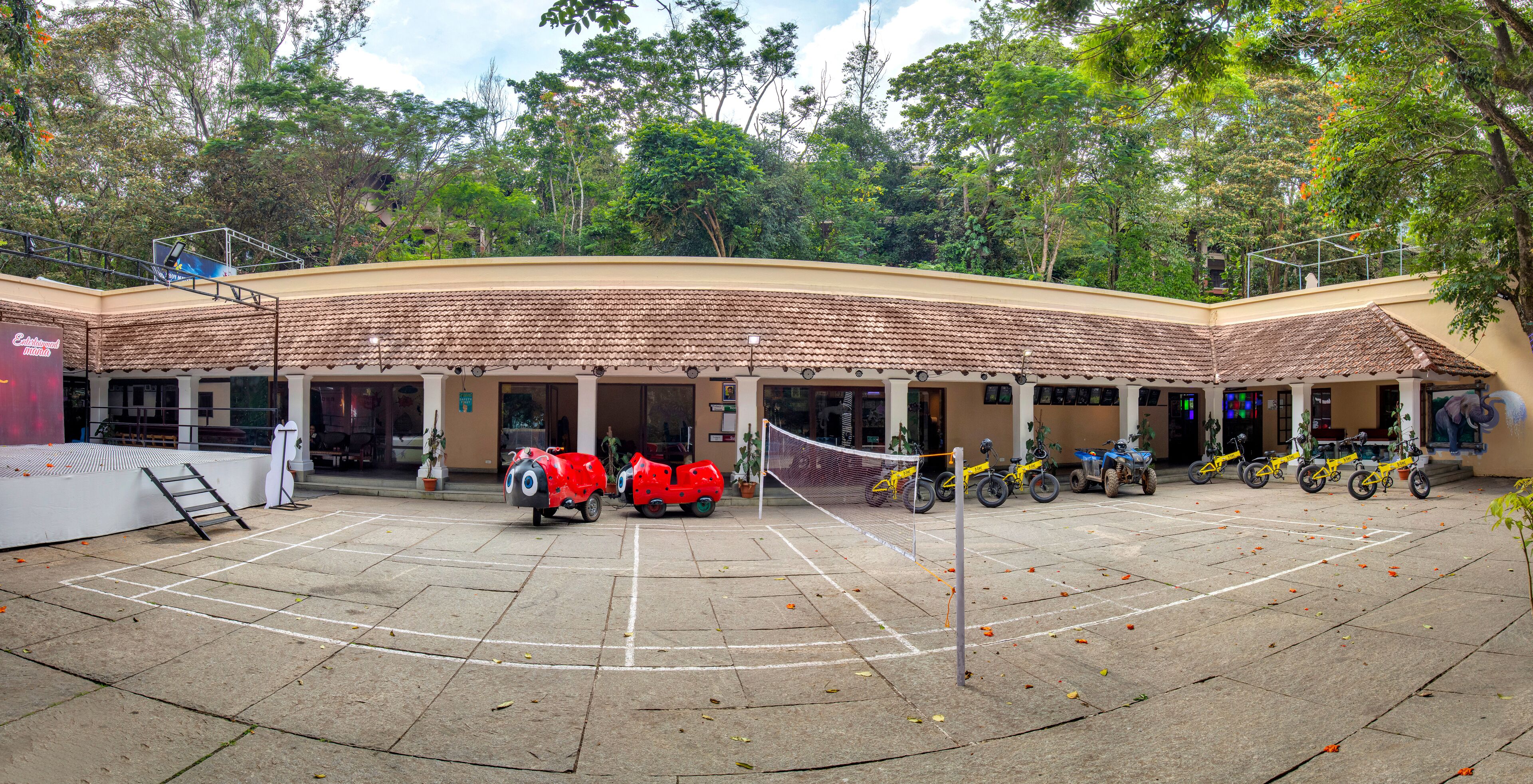 Un estacionamiento techado con cancha de baloncesto, bicicletas y un scooter.