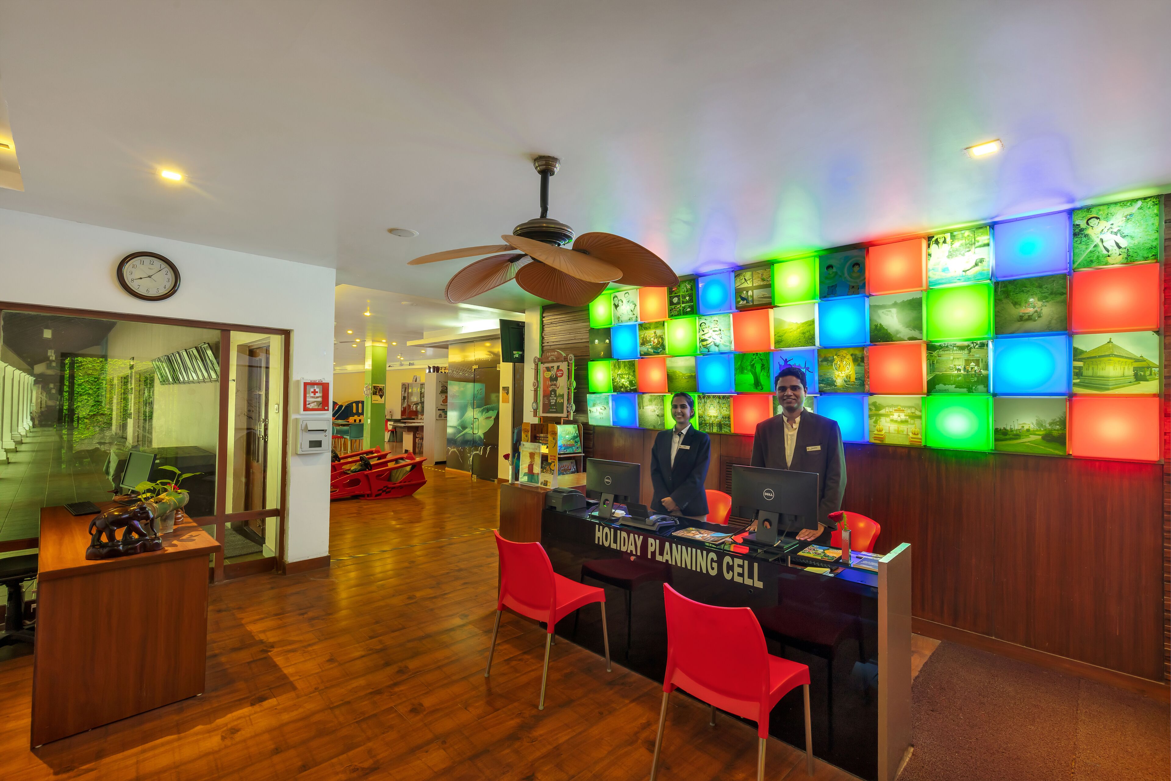 A holiday planning cell with two staff members, wooden flooring, and a wall of colorful illuminated panels.