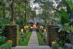 A pathway leading to a traditional-style building surrounded by lush greenery and stone walls. - Club Mahindra Madikeri, Coorg (Madikeri)