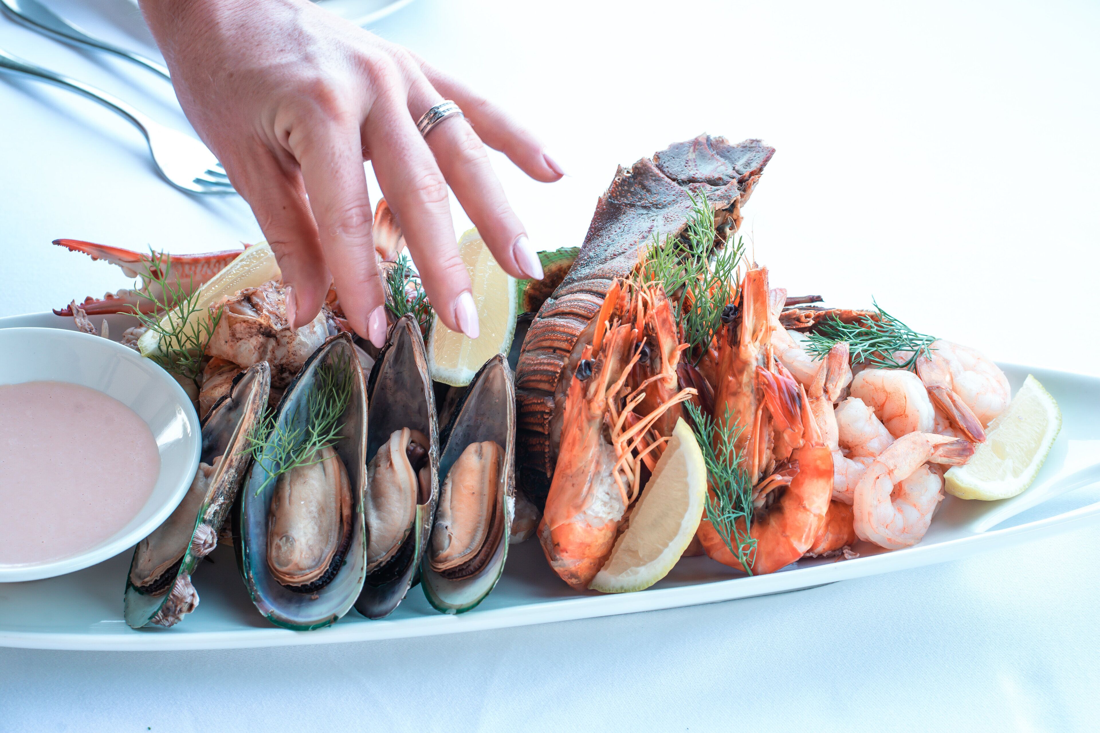 A seafood platter with various shellfish and shrimp, garnished with herbs and lemon slices.