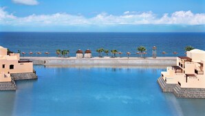 Un resort con piscina, palmeras y vistas al mar.