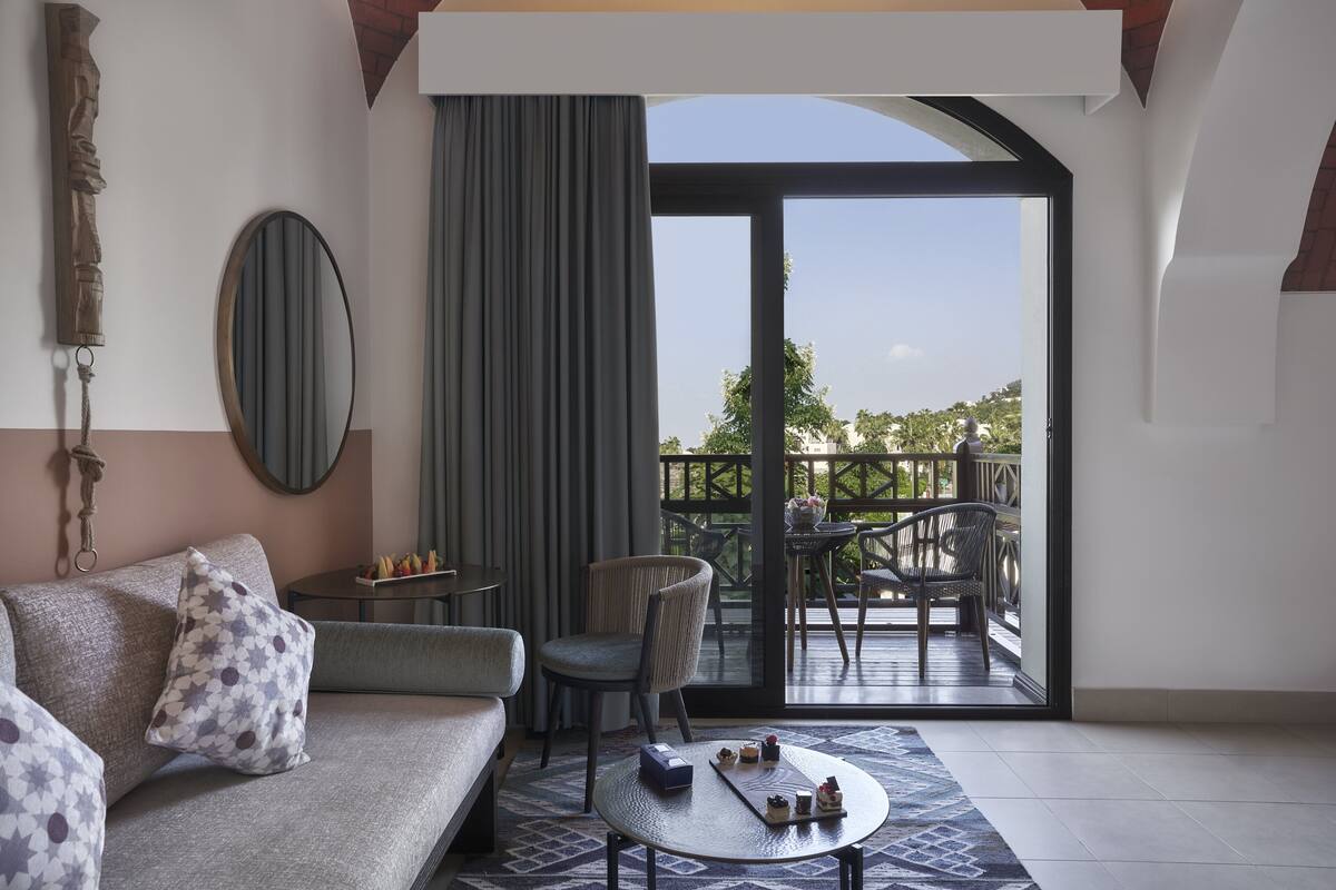 A modern living room with a sofa, chairs, a coffee table, and a balcony with outdoor furniture.