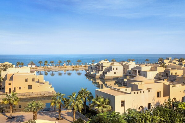 A coastal resort with multiple buildings, a calm pool, and palm trees. - The Cove Rotana Resort (Ras Al Khaimah)