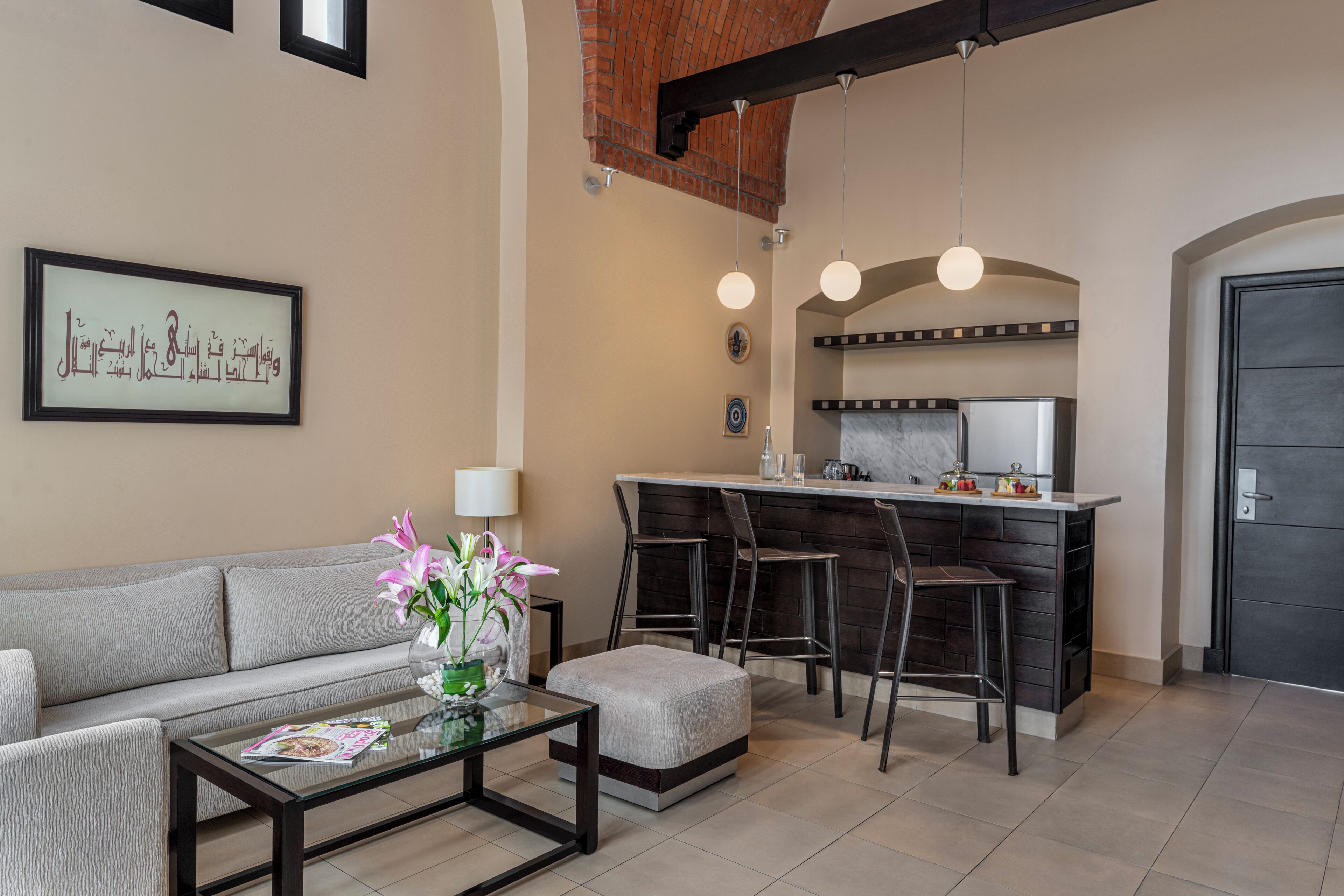 Un salon moderne comprenant un canapé, une table basse et un coin cuisine avec un bar.