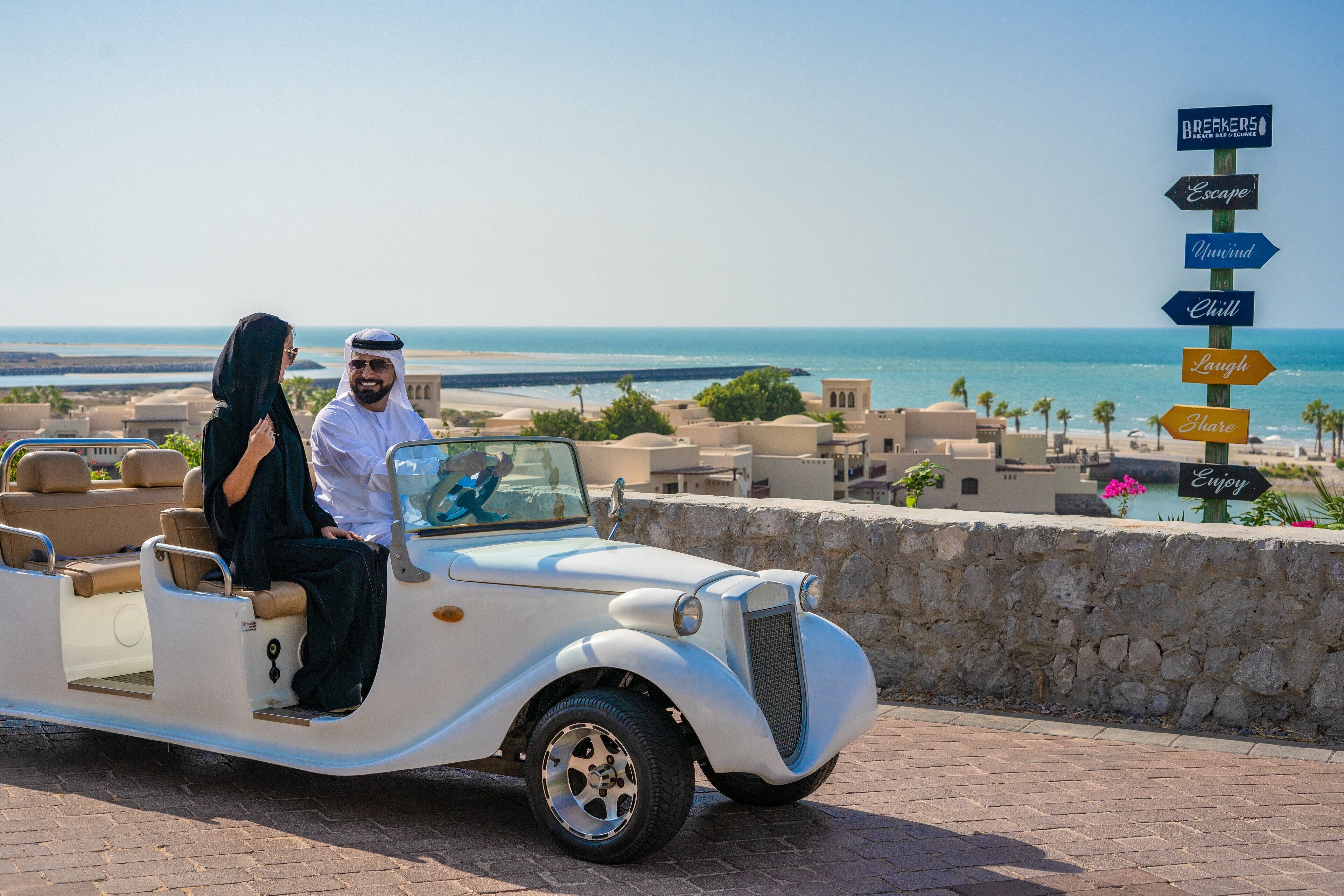 Un coche antiguo con una señalización que enumera actividades como 'Escapada,' 'Relájate,' 'Descansa,' 'Ríe,' 'Comparte' y 'Disfruta'.