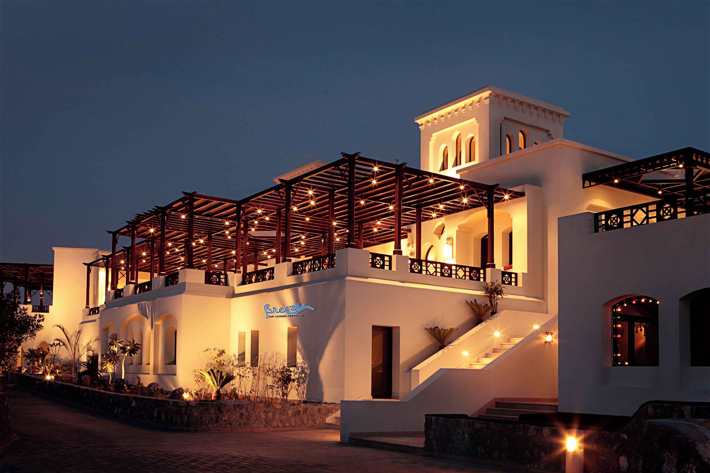 A modern hotel with a covered outdoor area, a staircase, and a sign indicating a lounge terrace.