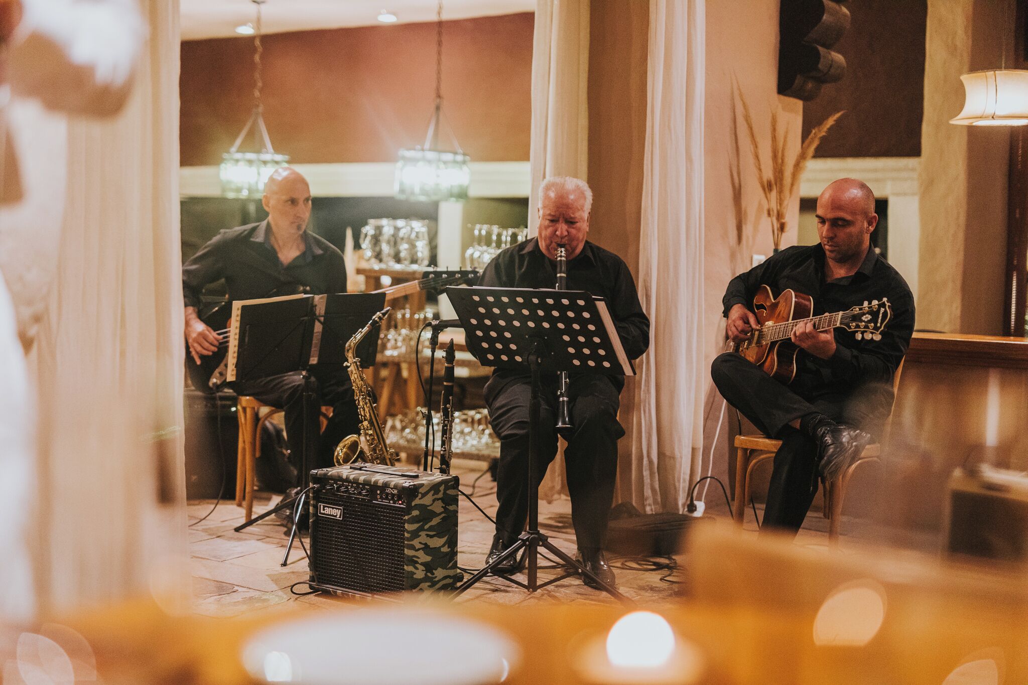 A band performing in a room with a piano, saxophone, and guitar.