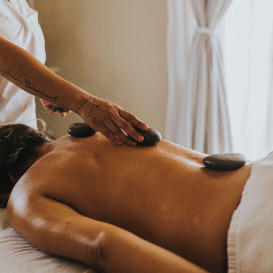 A person receiving a stone massage on a bed.