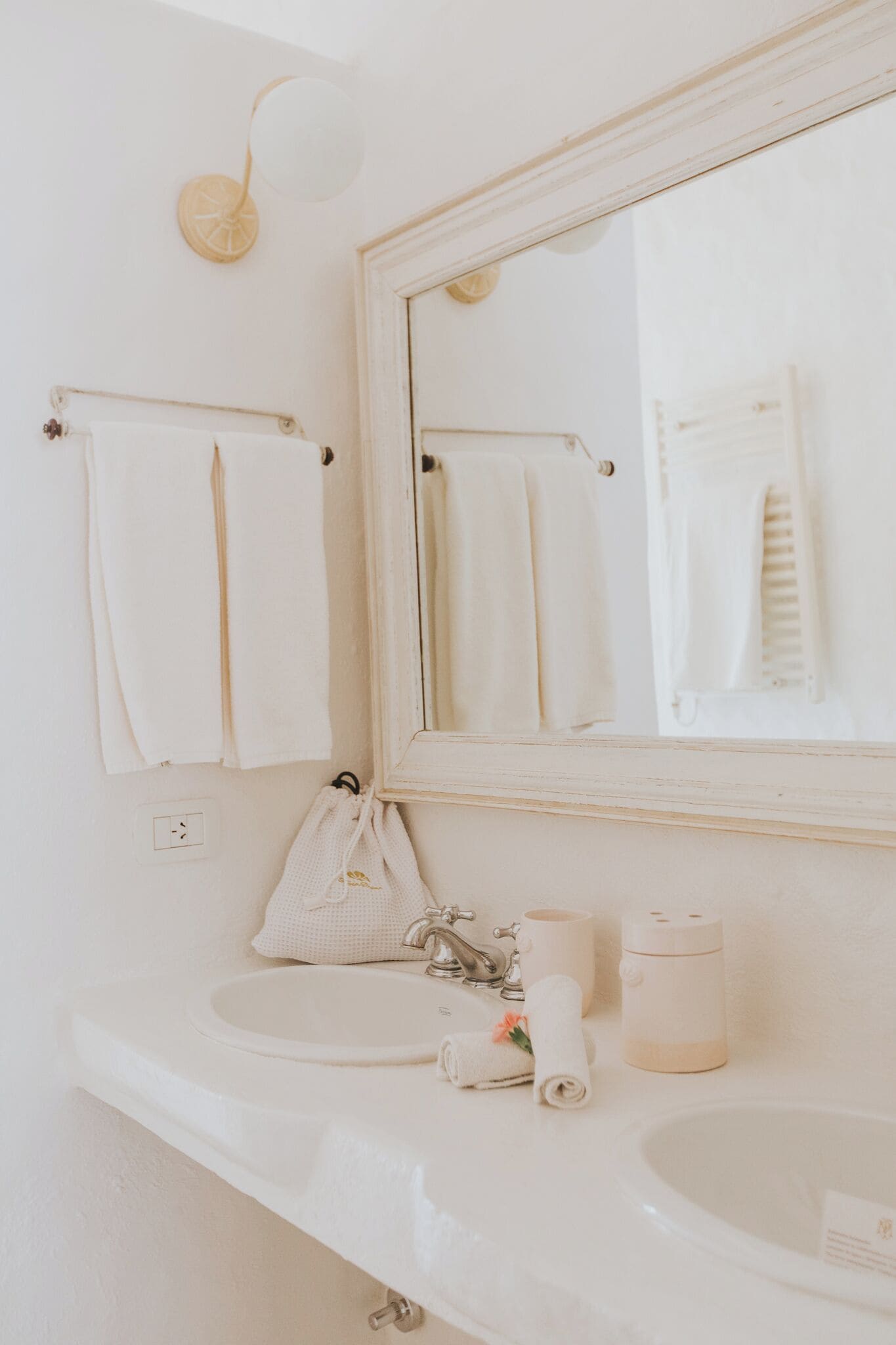 A bathroom with a white sink, a mirror, and two towels hanging on the wall.