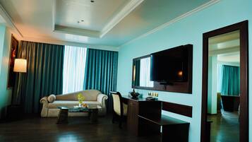 A hotel room with a sofa, a desk, a television, and a mirror.