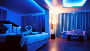 A modern hotel room with a large bed, a sofa, and a desk. - The Quilon Beach Hotel and Convention Center (Kollam)