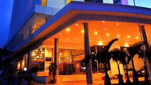 A modern hotel with a prominent vertical design, large windows, and a well-lit entrance area. - The Quilon Beach Hotel and Convention Center (Kollam)