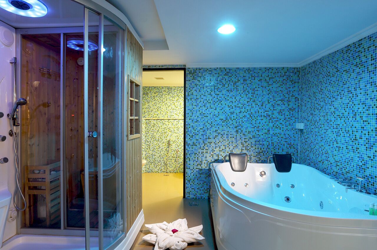 Un baño moderno con una bañera grande, una zona de ducha y una puerta de madera.