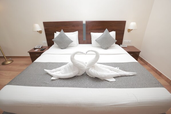 Habitación de hotel con una cama bien hecha, dos mesitas de noche con lámparas y un teléfono en la pared.