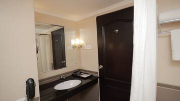 A hotel bathroom with a dark wooden door, a white sink, a mirror, and a telephone.