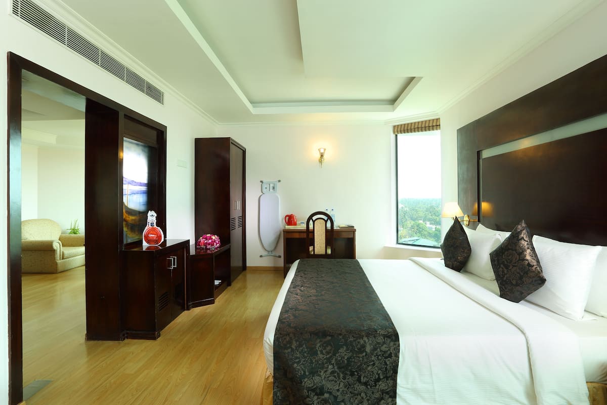 Habitación de hotel con cama, escritorio, silla, armario y un espejo grande.