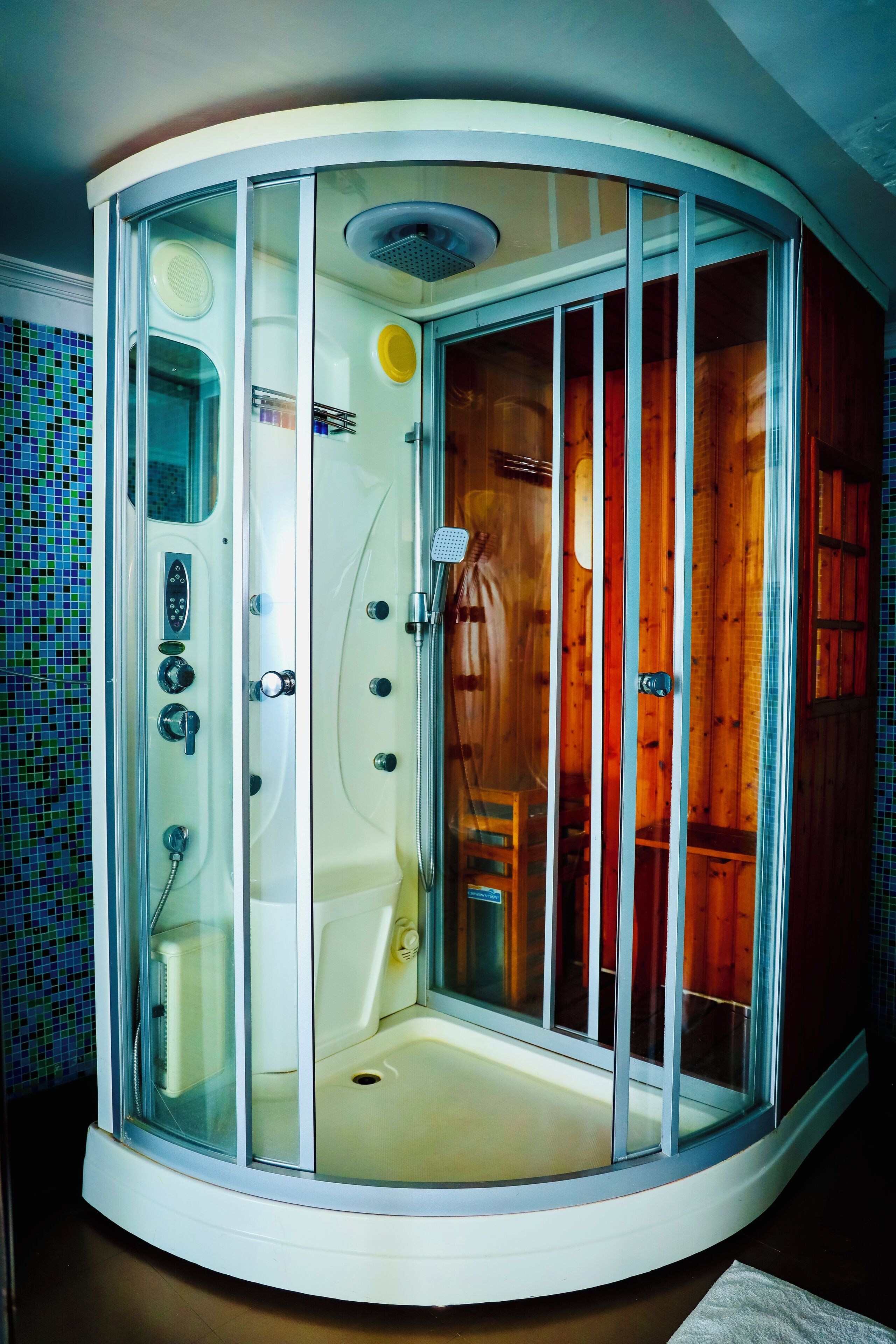 A corner shower enclosure with a glass door, a control panel, and a showerhead.