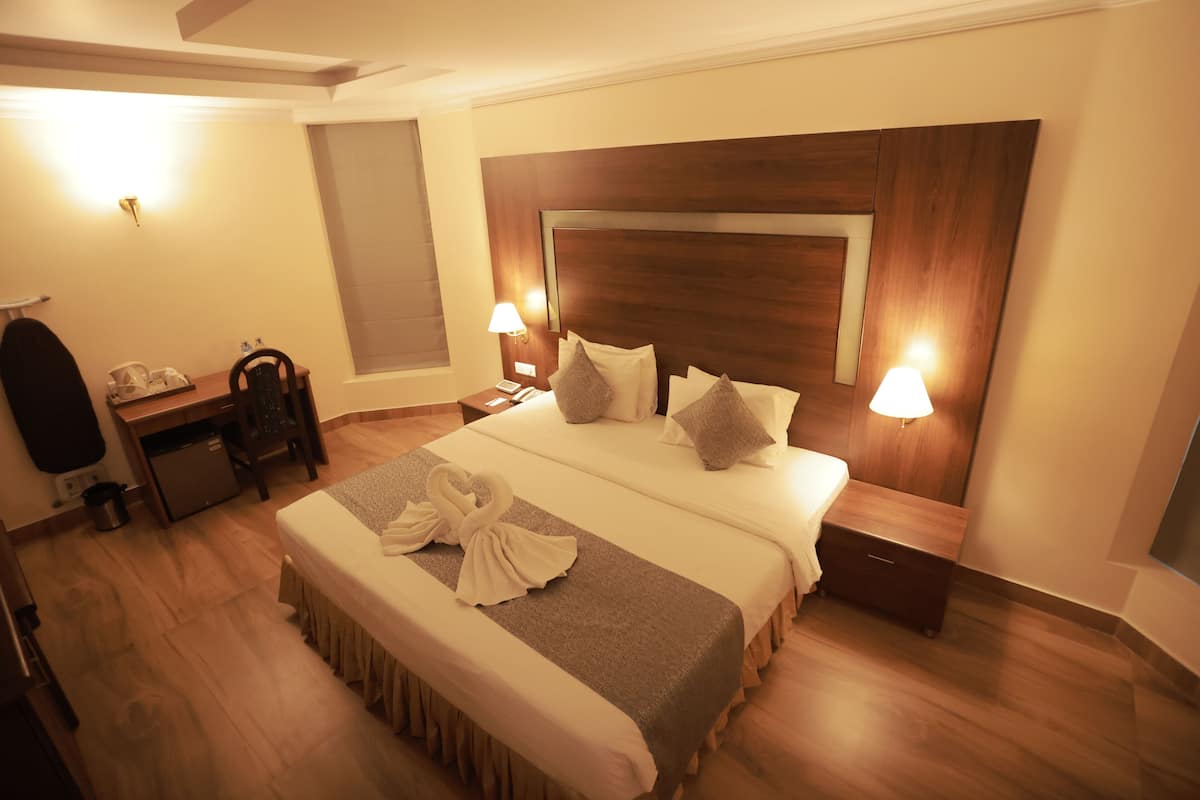 Habitación de hotel con una cama grande, dos mesitas de noche con lámparas, un escritorio con una silla y un armario.