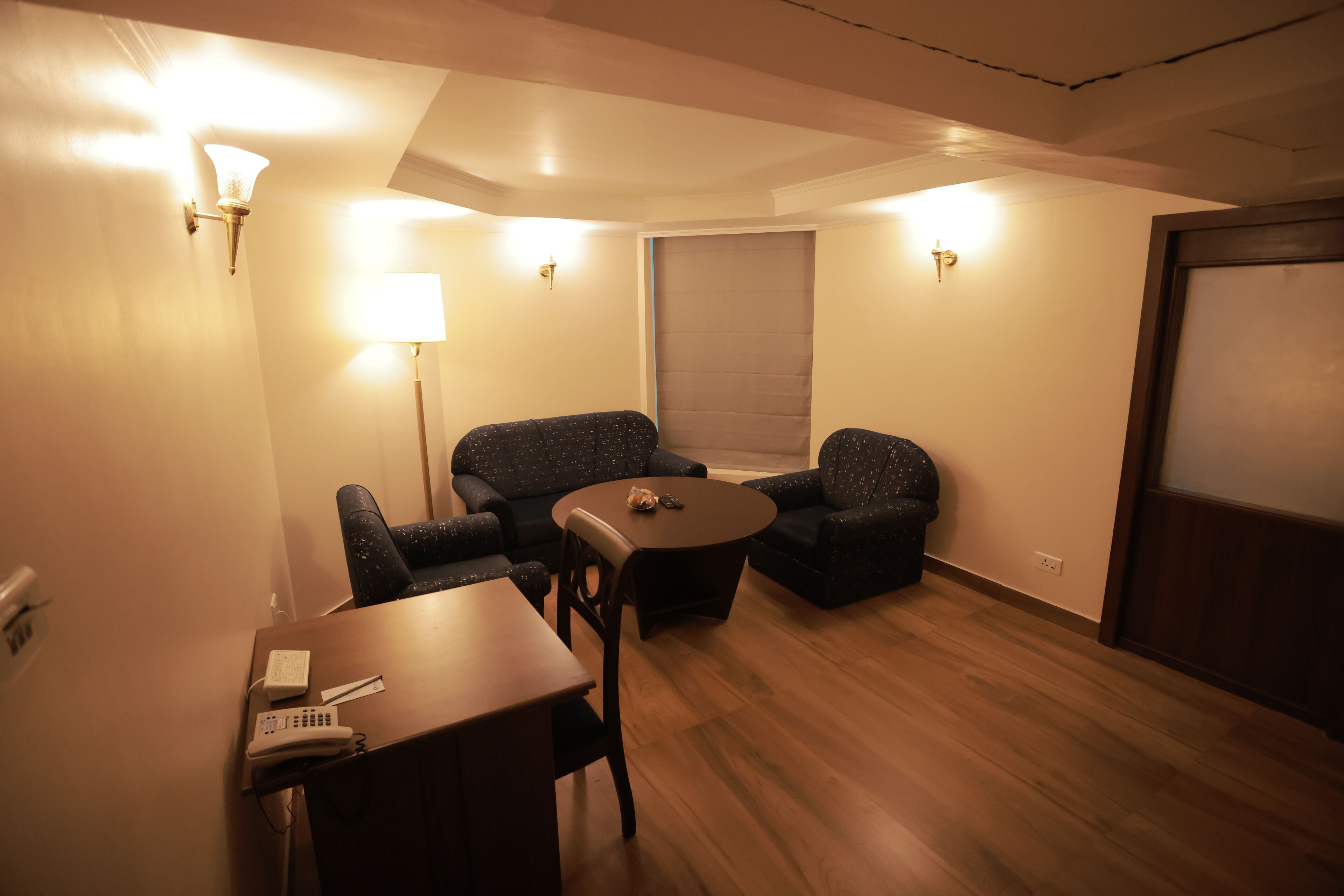 A small, cozy room with two upholstered chairs, a small round table, and a lamp.