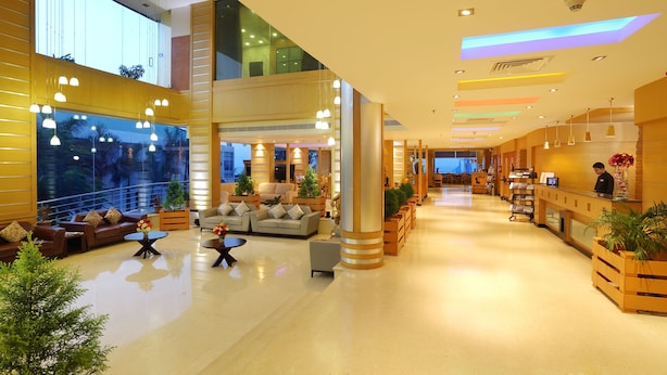 A spacious lobby with a reception desk, seating area, and large windows offering views. - The Quilon Beach Hotel and Convention Center (Kollam)