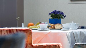A table set with a teapot, cups, a plate of bread, and a potted plant. - Olympic Star (Patras)