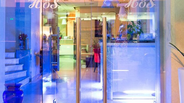 A hotel entrance with glass doors, a reception desk, and a visible interior space with a sofa and a plant. - Olympic Star (Patras)