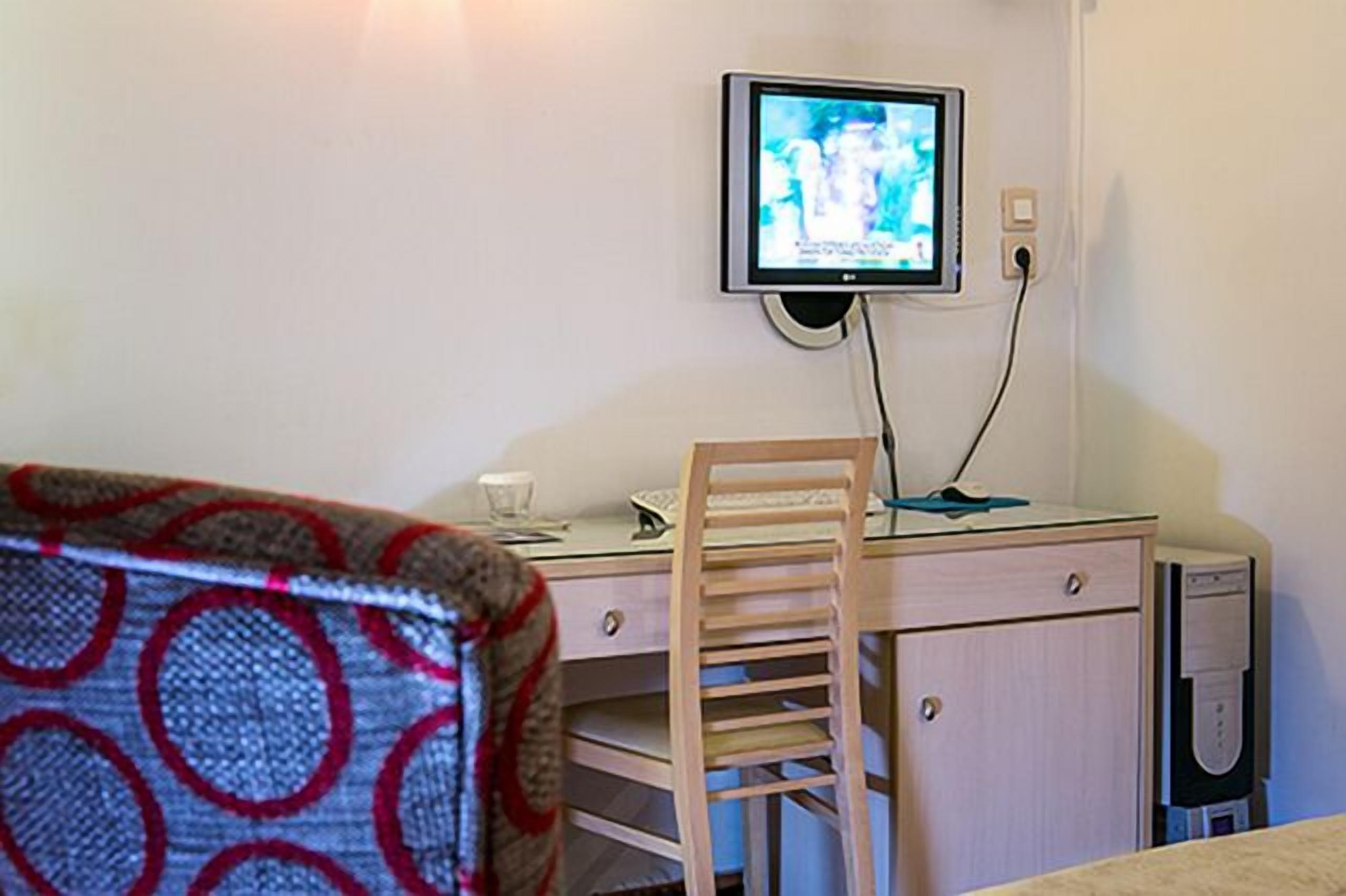 Una habitación pequeña con un escritorio, una silla y un televisor montado en la pared.