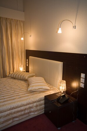 A neatly made bed with striped bedding, a bedside lamp, and a telephone on a nightstand.