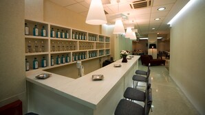 A modern bar area with shelves of bottles, a long counter, and bar stools. - Olympic Star (Patras)