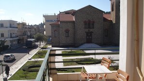 Un balcone con posti a sedere all'aperto, un edificio in pietra sullo sfondo e cielo sereno.
