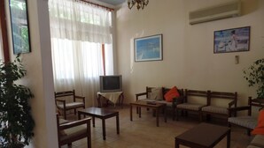 Un soggiorno con televisione, divano, poltrone e tavolo.