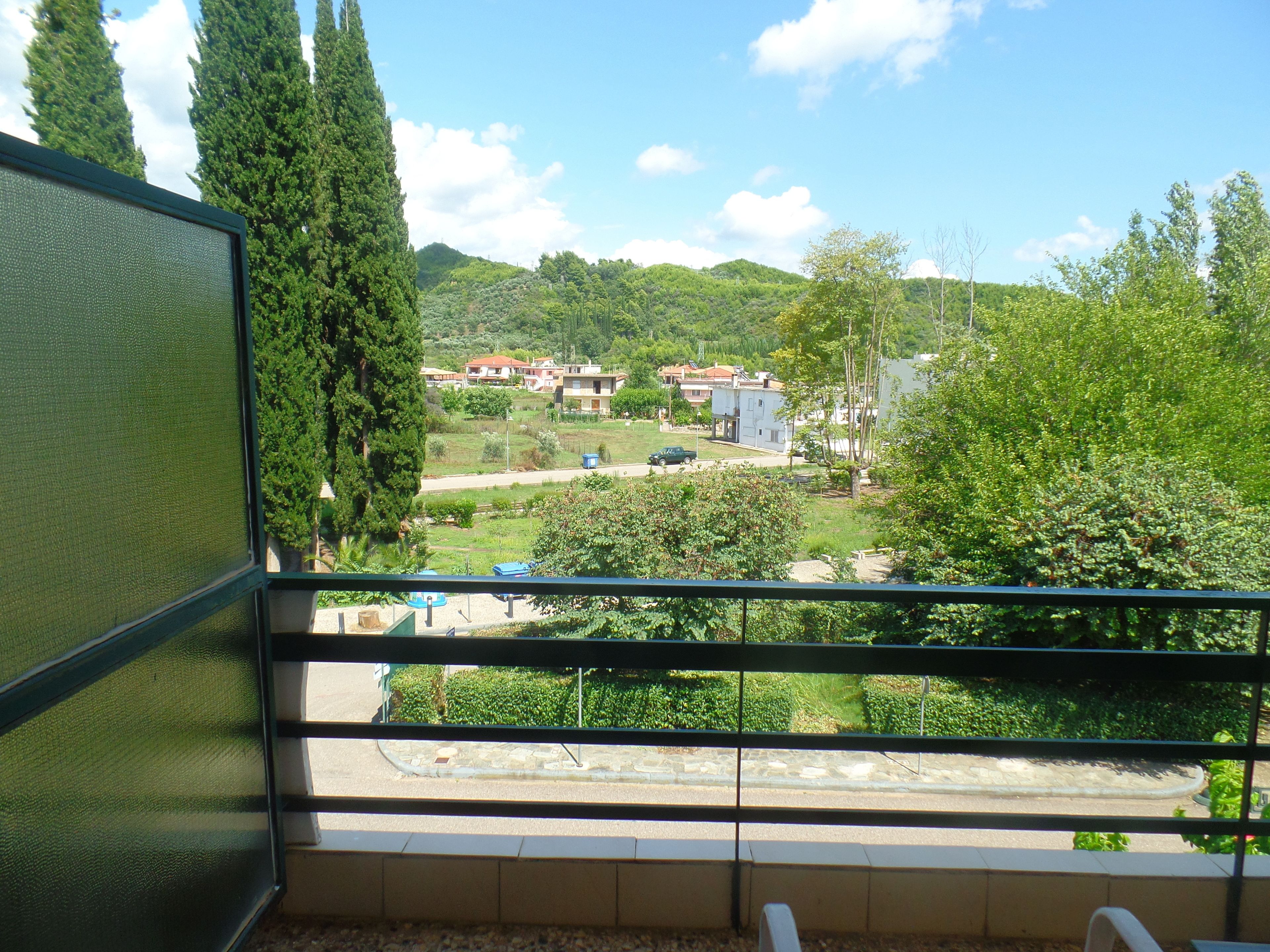Un balcón con vista a una zona residencial, con casas y vegetación.