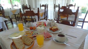 Una tavola imbandita per la colazione con pane, uova, prosciutto, succo e caffè.