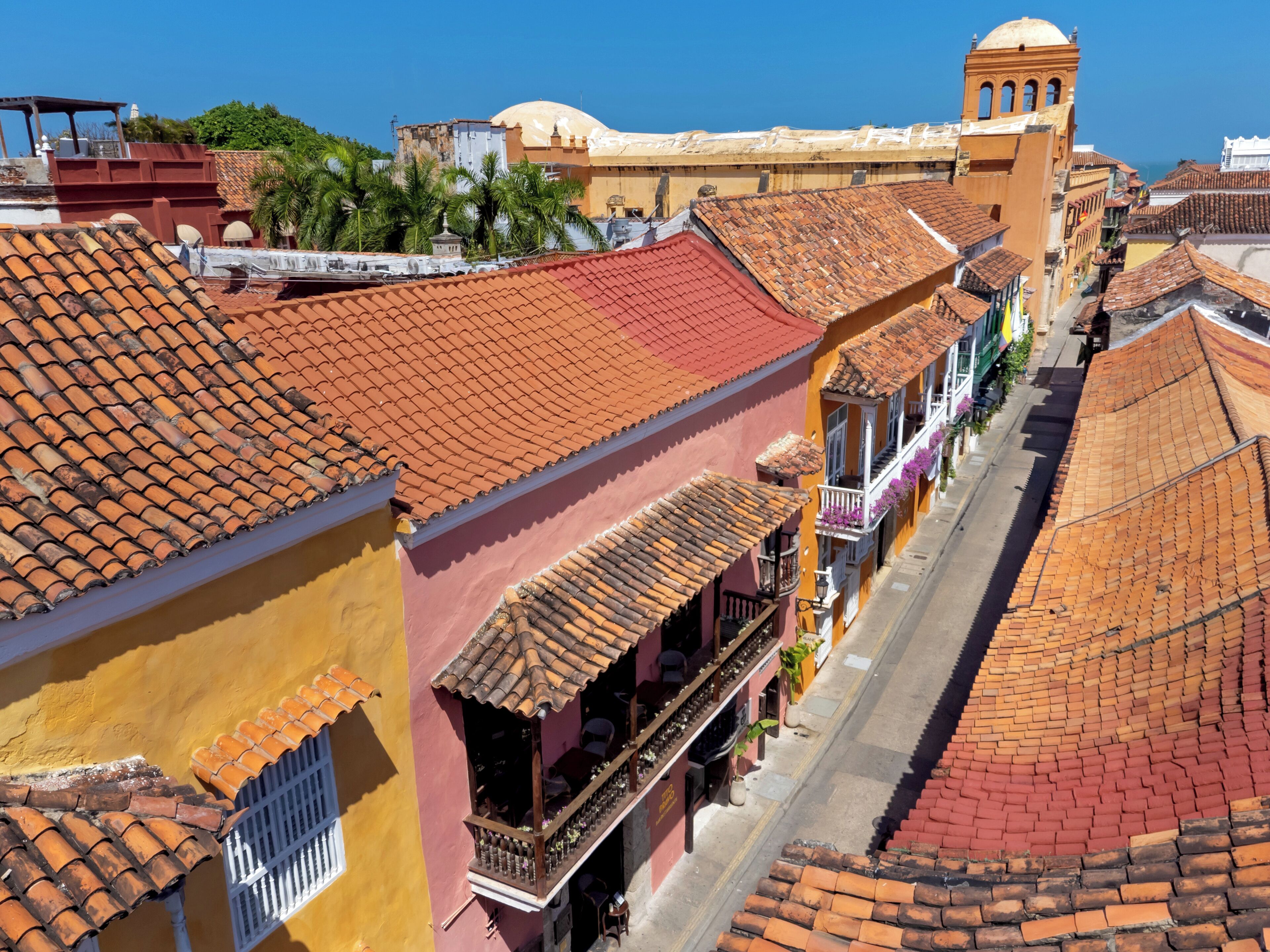 Vista de la calle con edificios que tienen techos de tejas rojas y balcones.