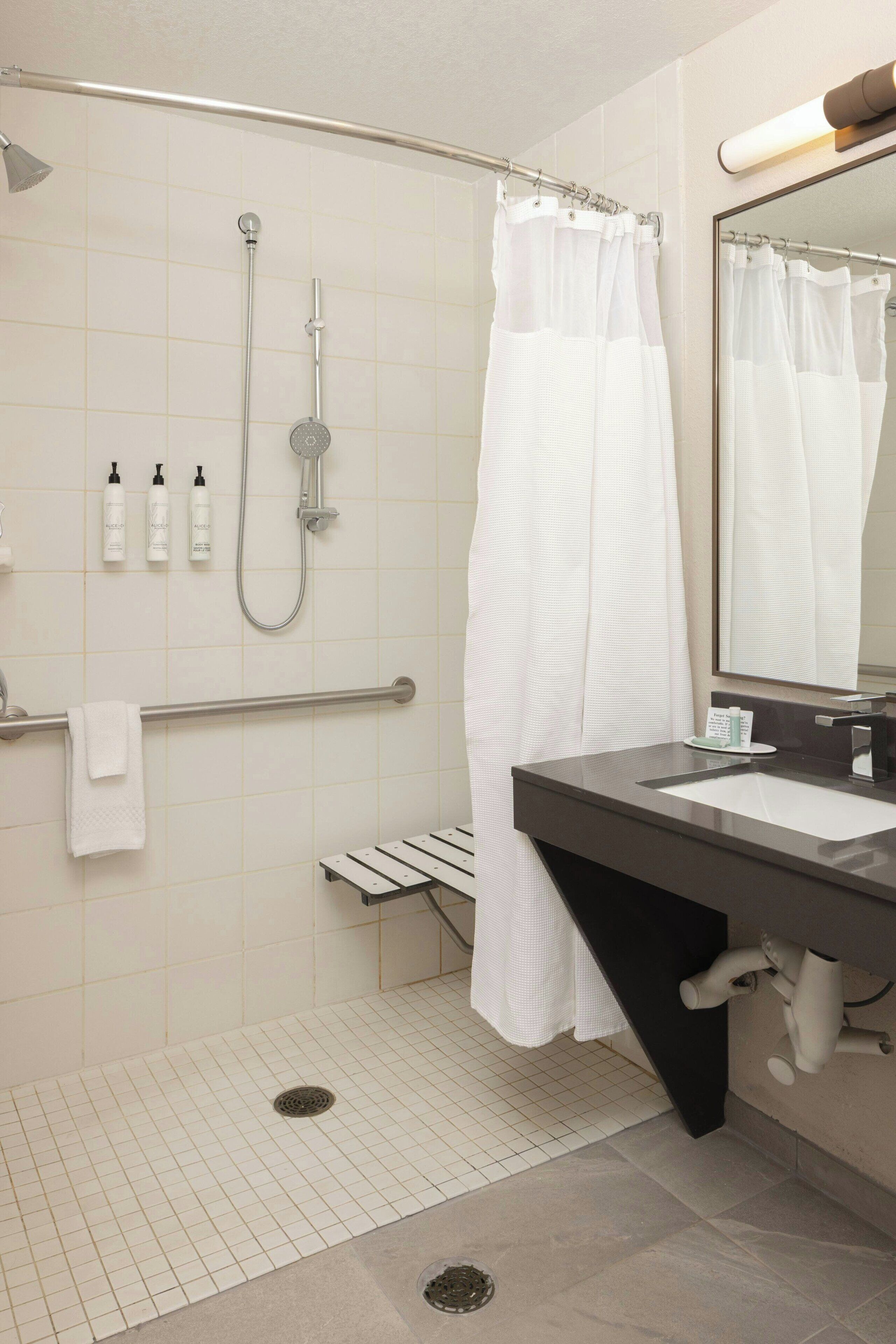 A modern bathroom with a shower, a vanity with a mirror, and a towel rack.