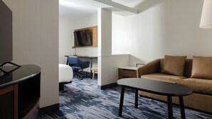 Una habitación de hotel con cama, escritorio, sofá y televisor.
