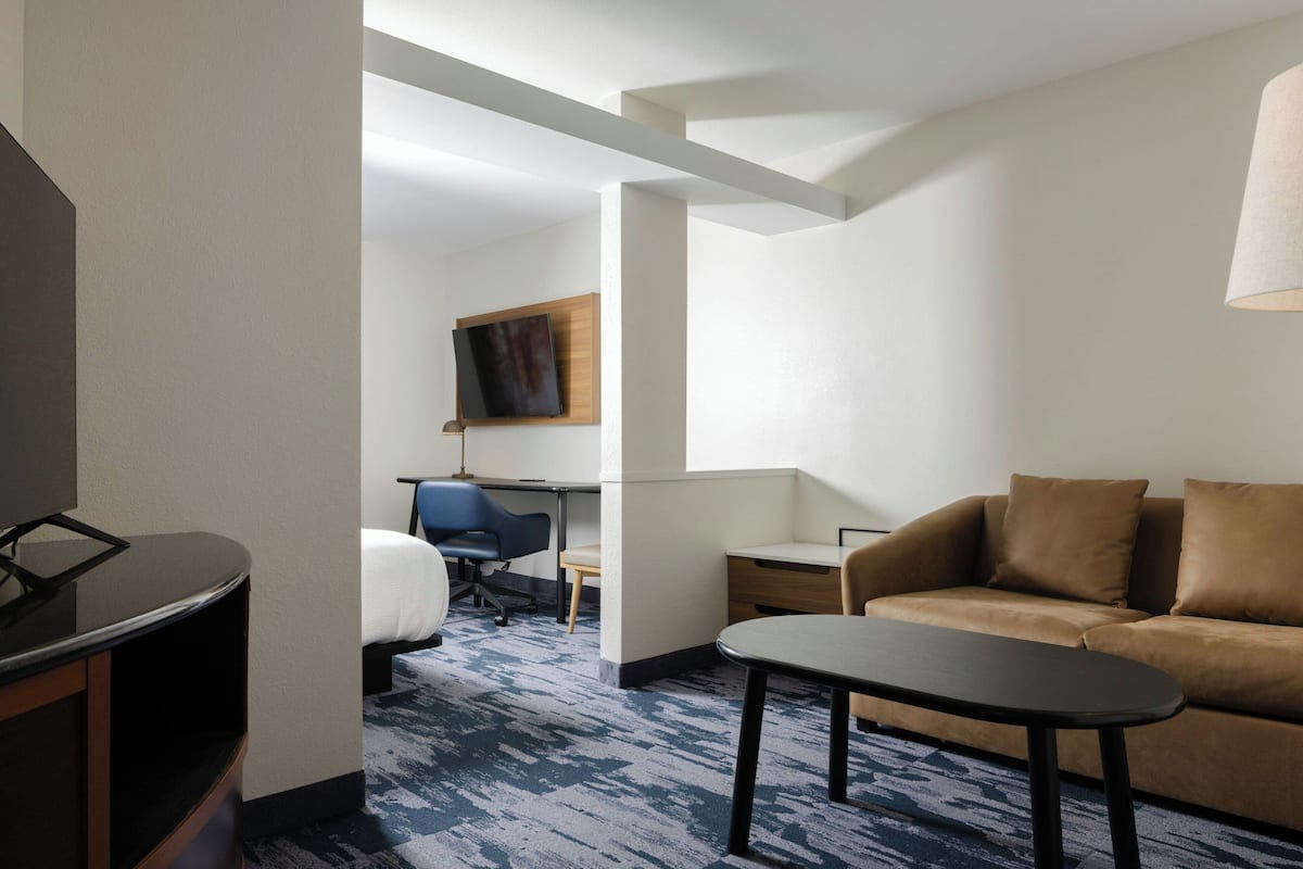 Una habitación de hotel con cama, escritorio, sofá y televisor.