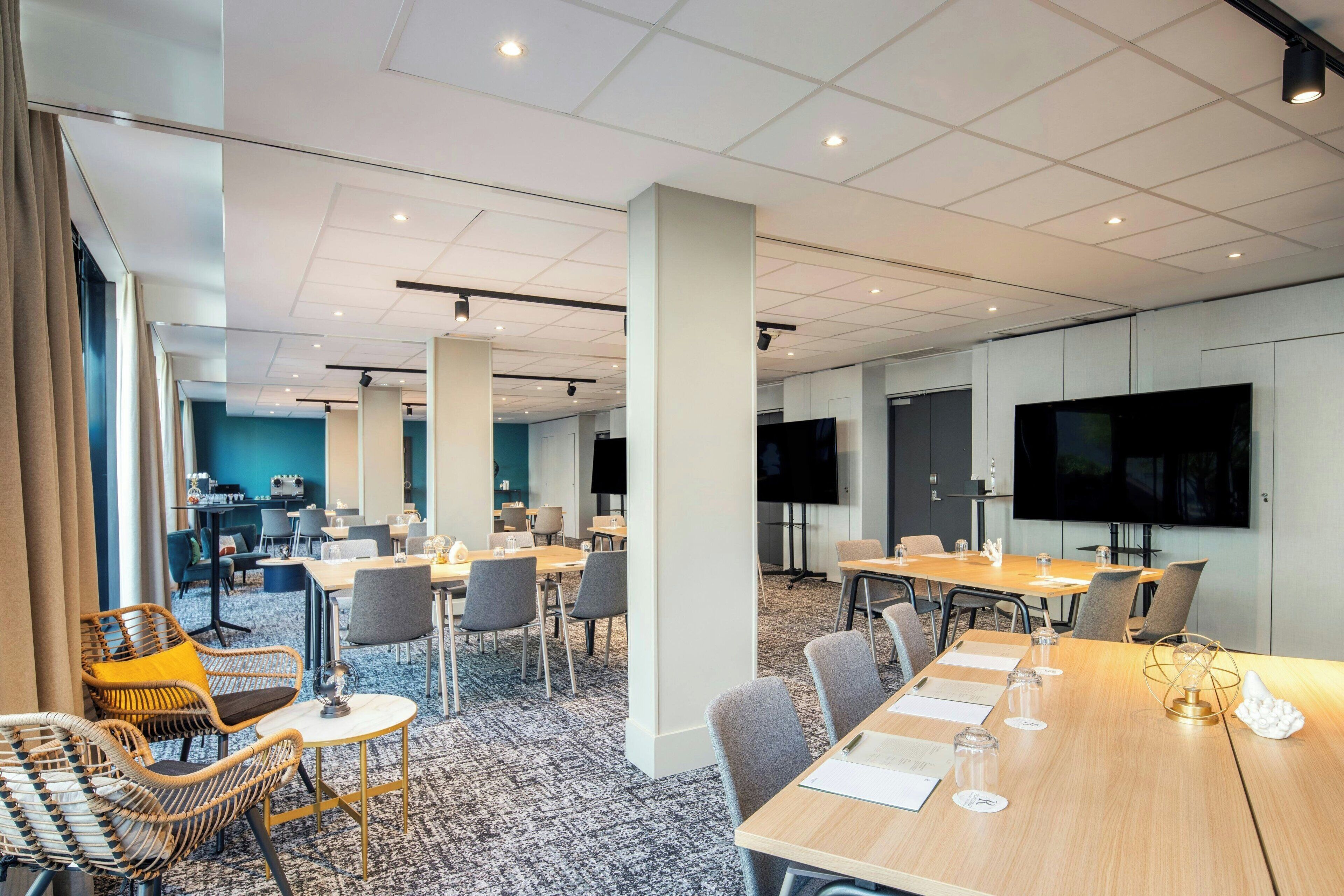 A modern conference room with a large table, chairs, and a television screen.