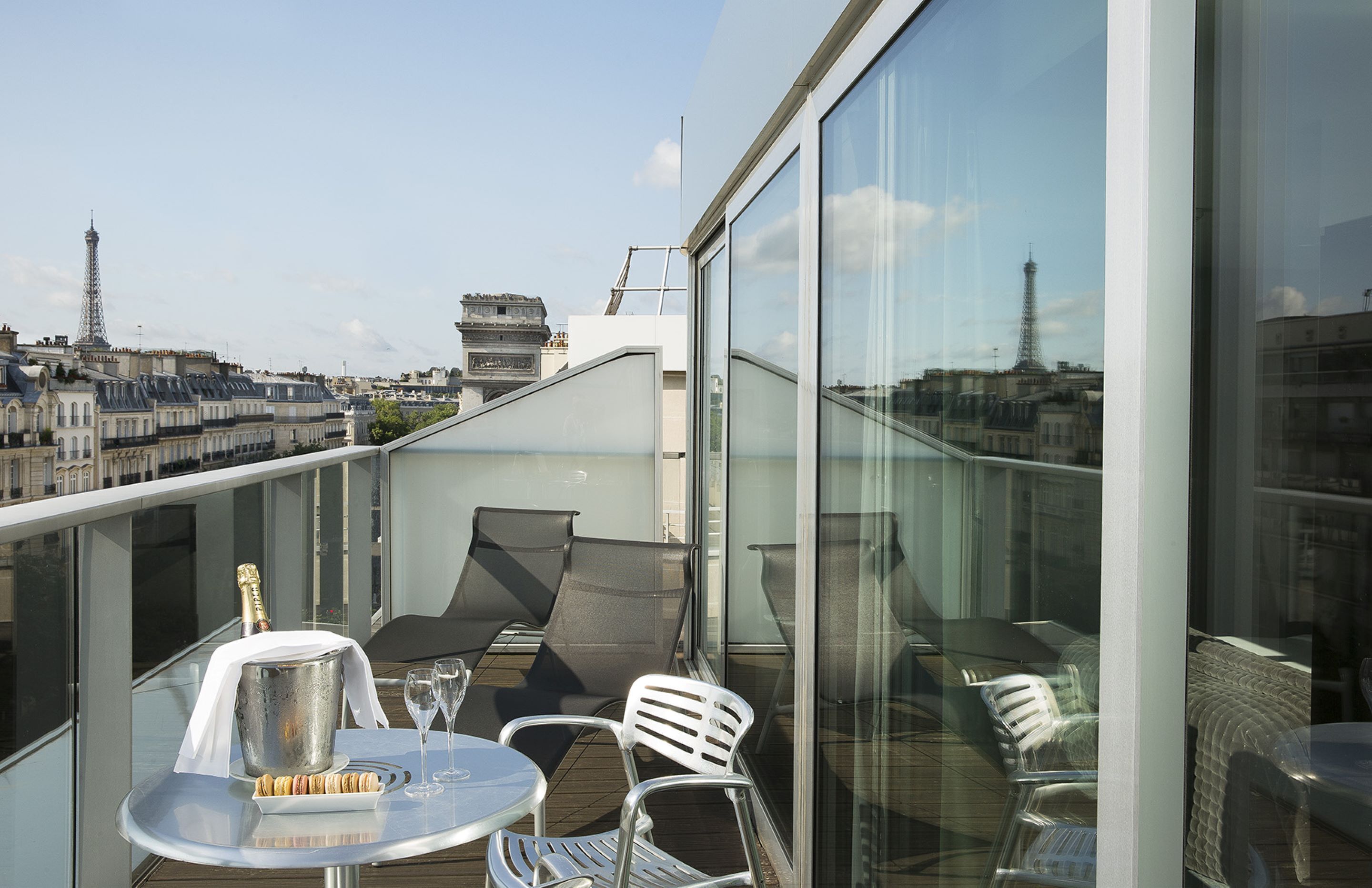 Un balcón con una mesa, sillas, un cubo para champán y vistas de la Torre Eiffel.