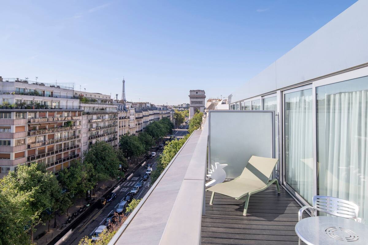 Un balcon offrant une vue sur le paysage urbain, avec notamment une tour et un monument.