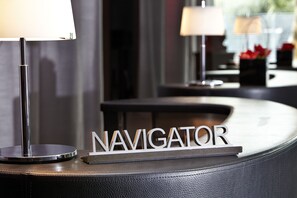 A reception desk with a sign reading "NAVIGATOR" and a lamp on the left. - Renaissance Paris Arc de Triomphe Hotel (Paris)