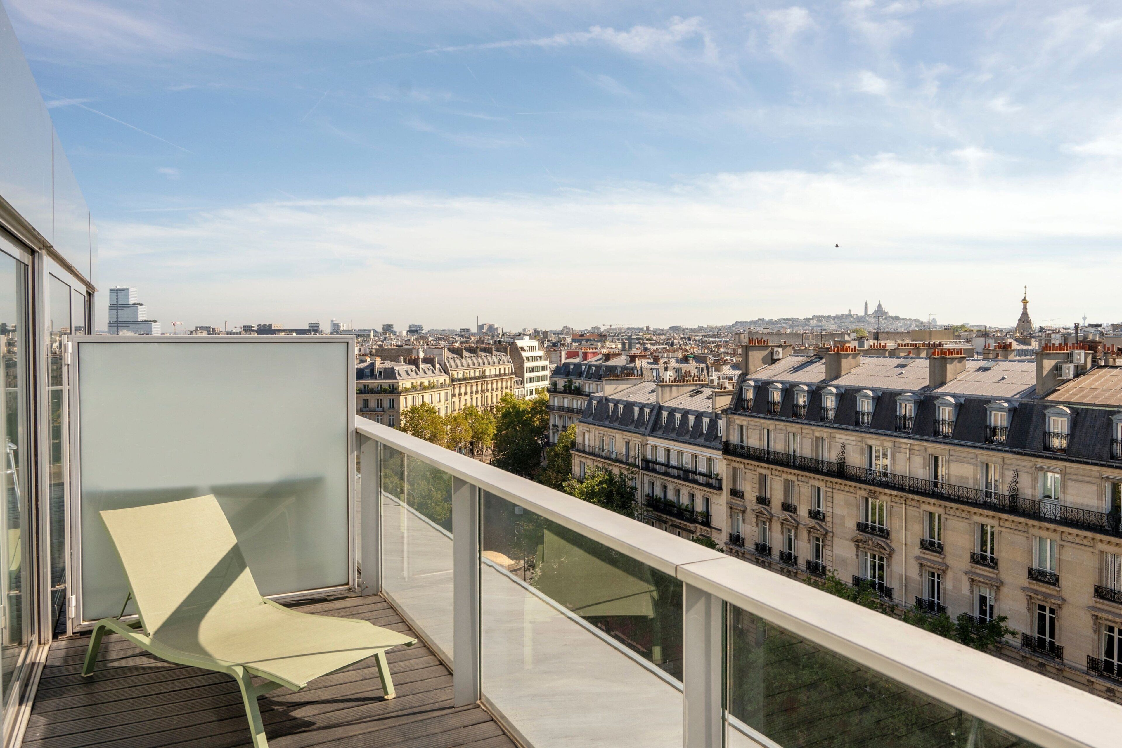 A balcony with a view of a cityscape, including historic buildings and a tower.