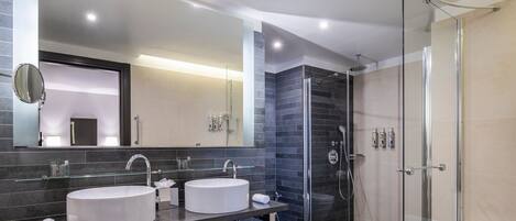 A modern bathroom with two sinks, a large mirror, and a glass-enclosed shower.