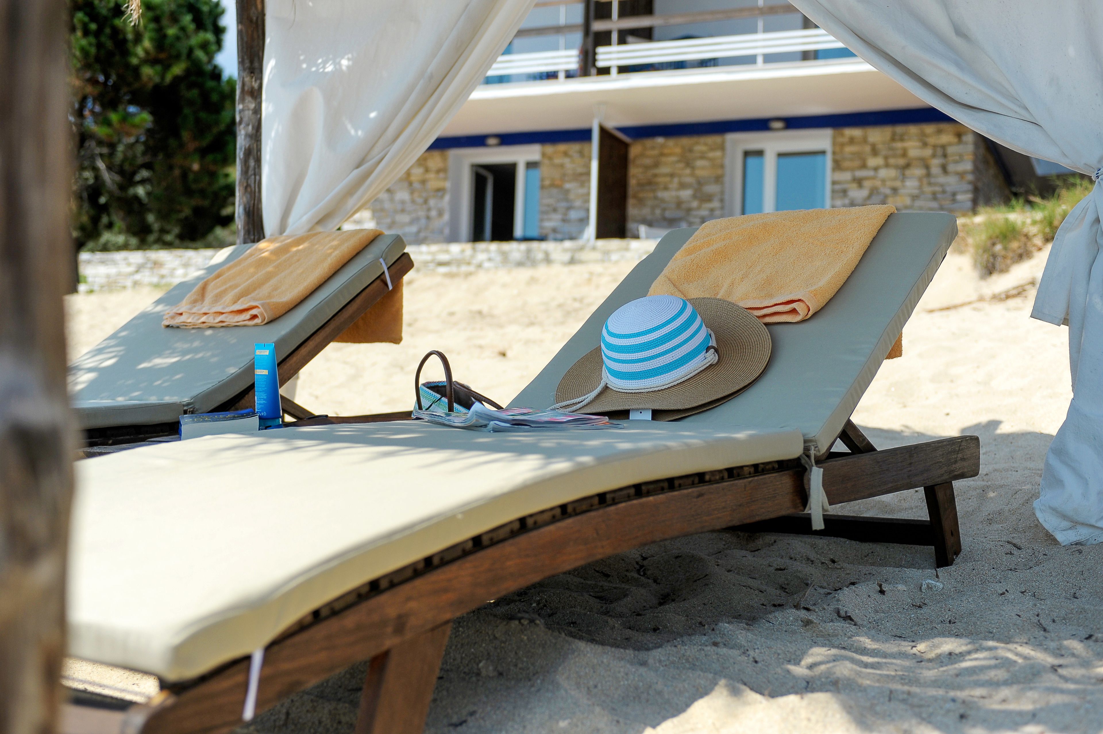 Two sun loungers with towels and a hat, a bottle, and a straw hat on one.