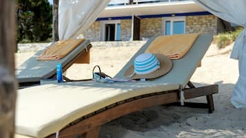 Two sun loungers with towels and a hat, a bottle, and a straw hat on one.