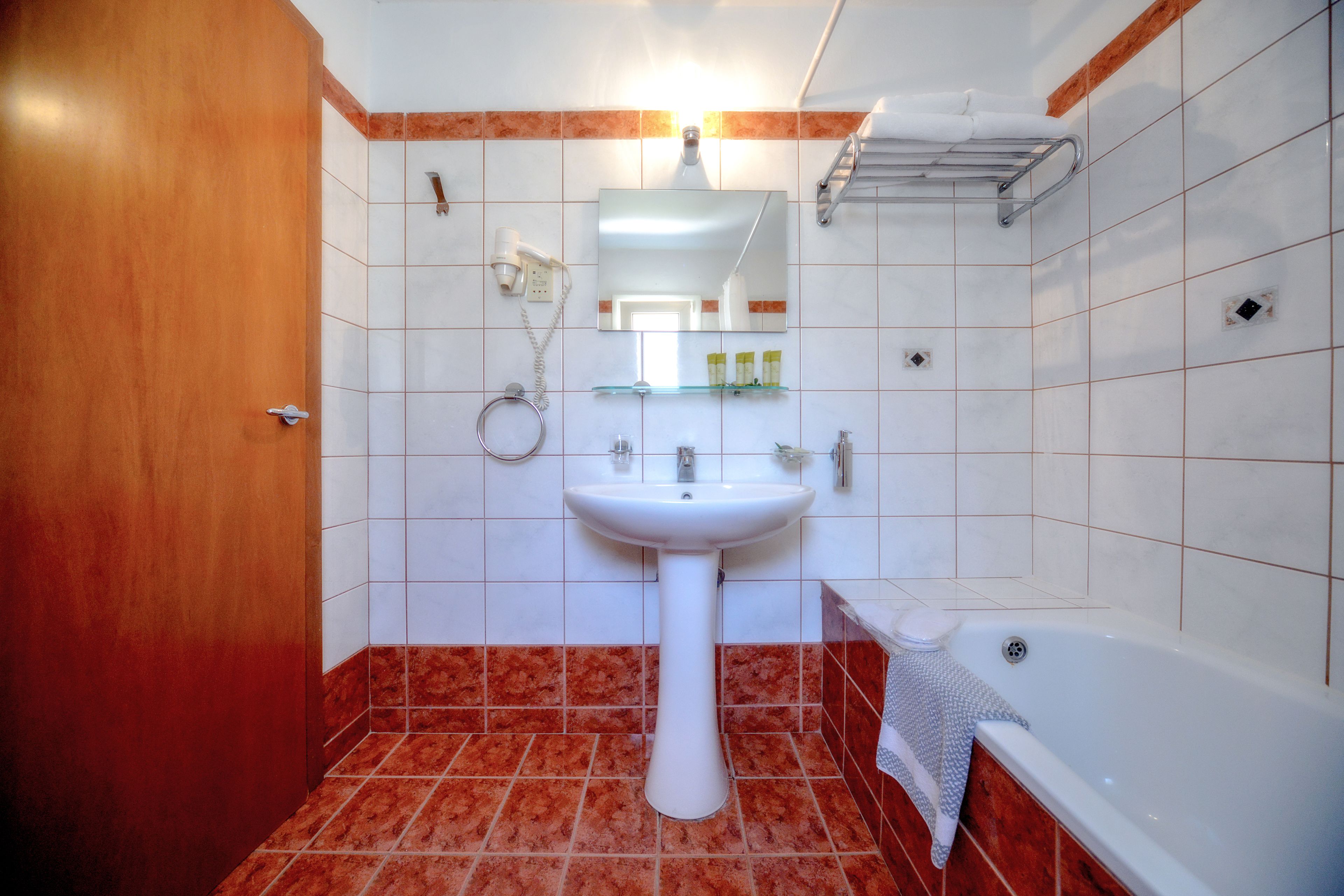 A bathroom with a white sink, mirror, and bathtub.